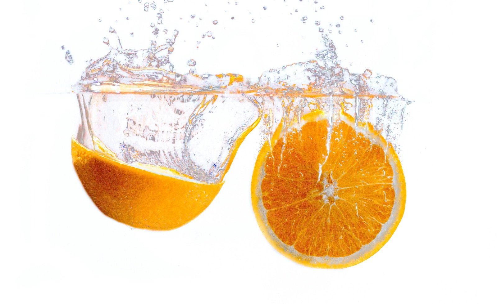 Fresh orange halves splashing into water